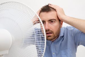 Flushed Man Feeling Hot In Front Of A Fan
